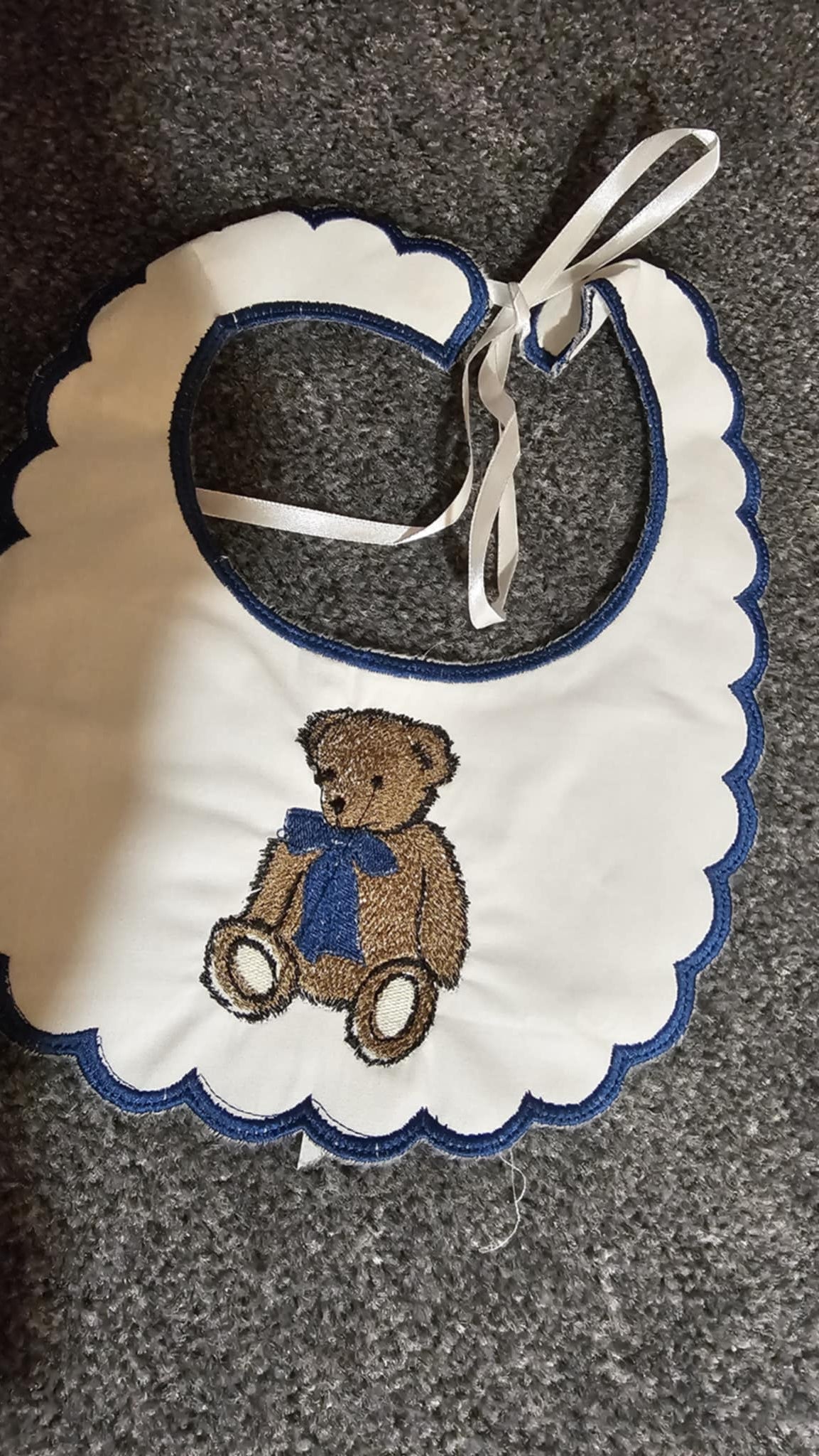 Baby bib with teddy bear design on a textured surface