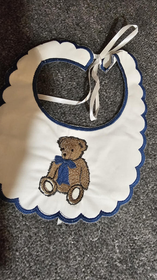 Baby bib with teddy bear design on a textured surface